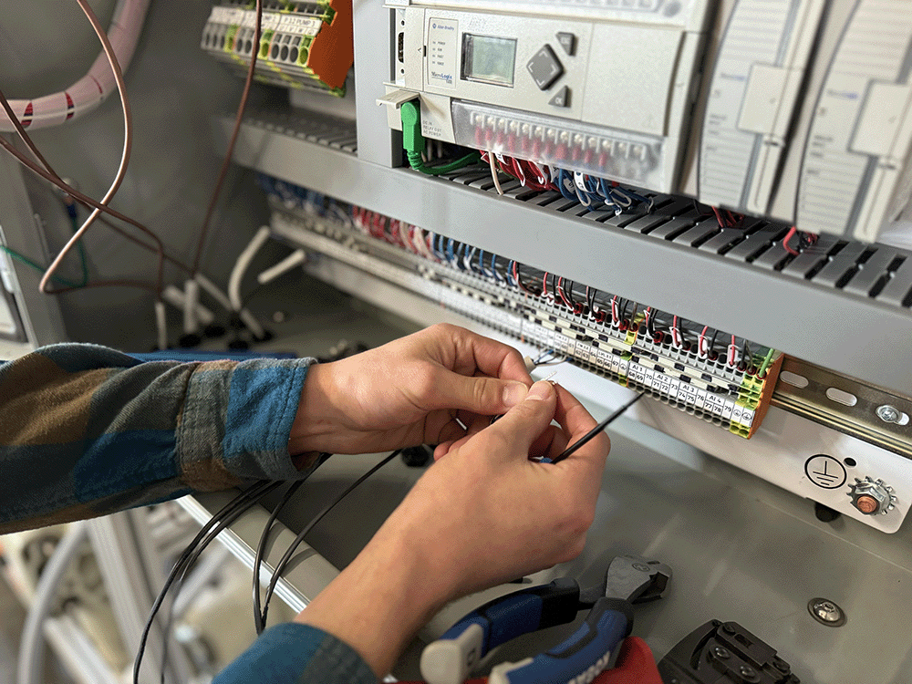 Photo containing PPT technician working on electrical panel for water system